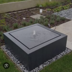 Rectangular Corten steel water feature with a rust-brown weathered finish, recirculating water within a framed basin on light gravel.